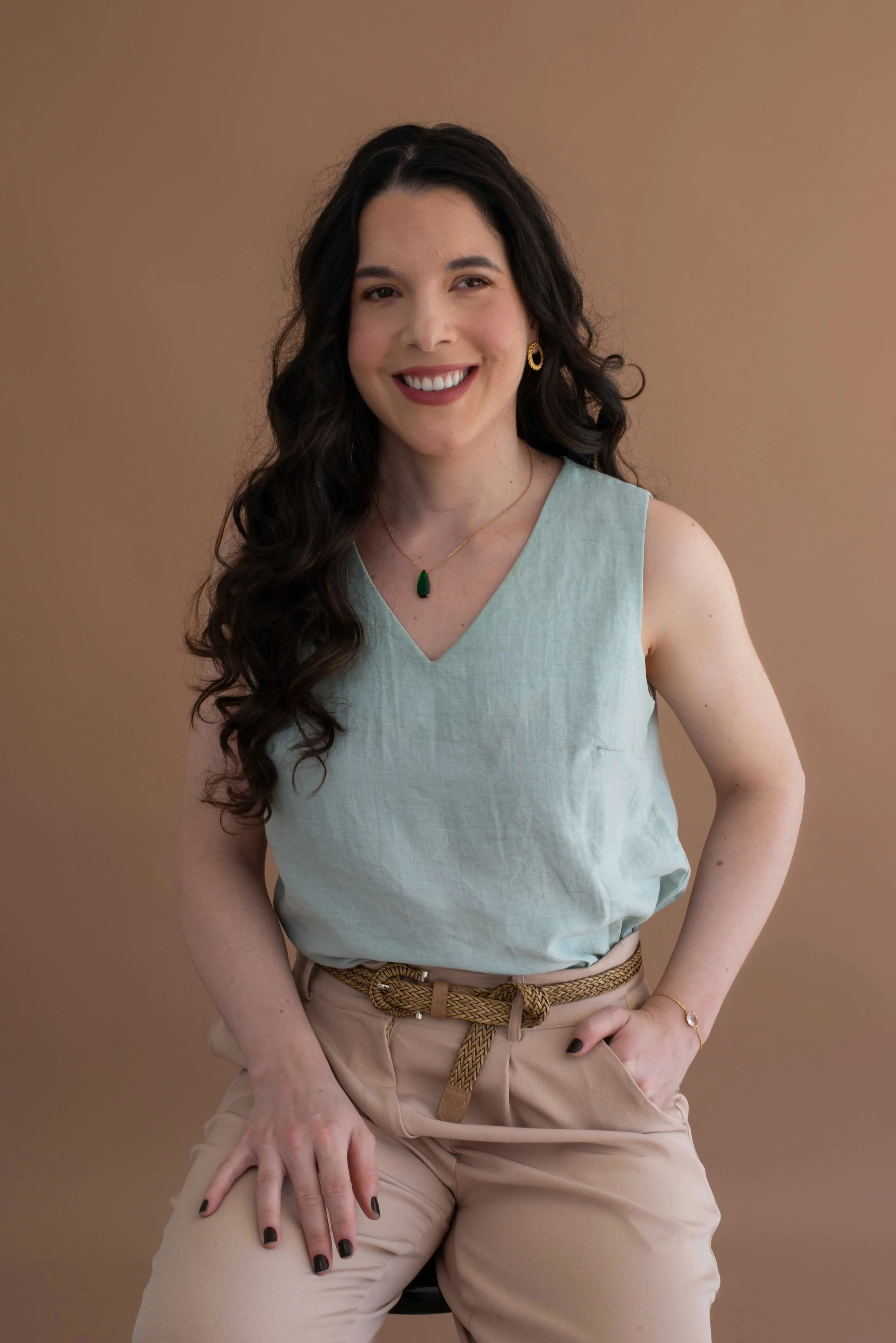 Profissional sentada no tapete, sorrindo para a câmera em ambiente claro e aconchegante.