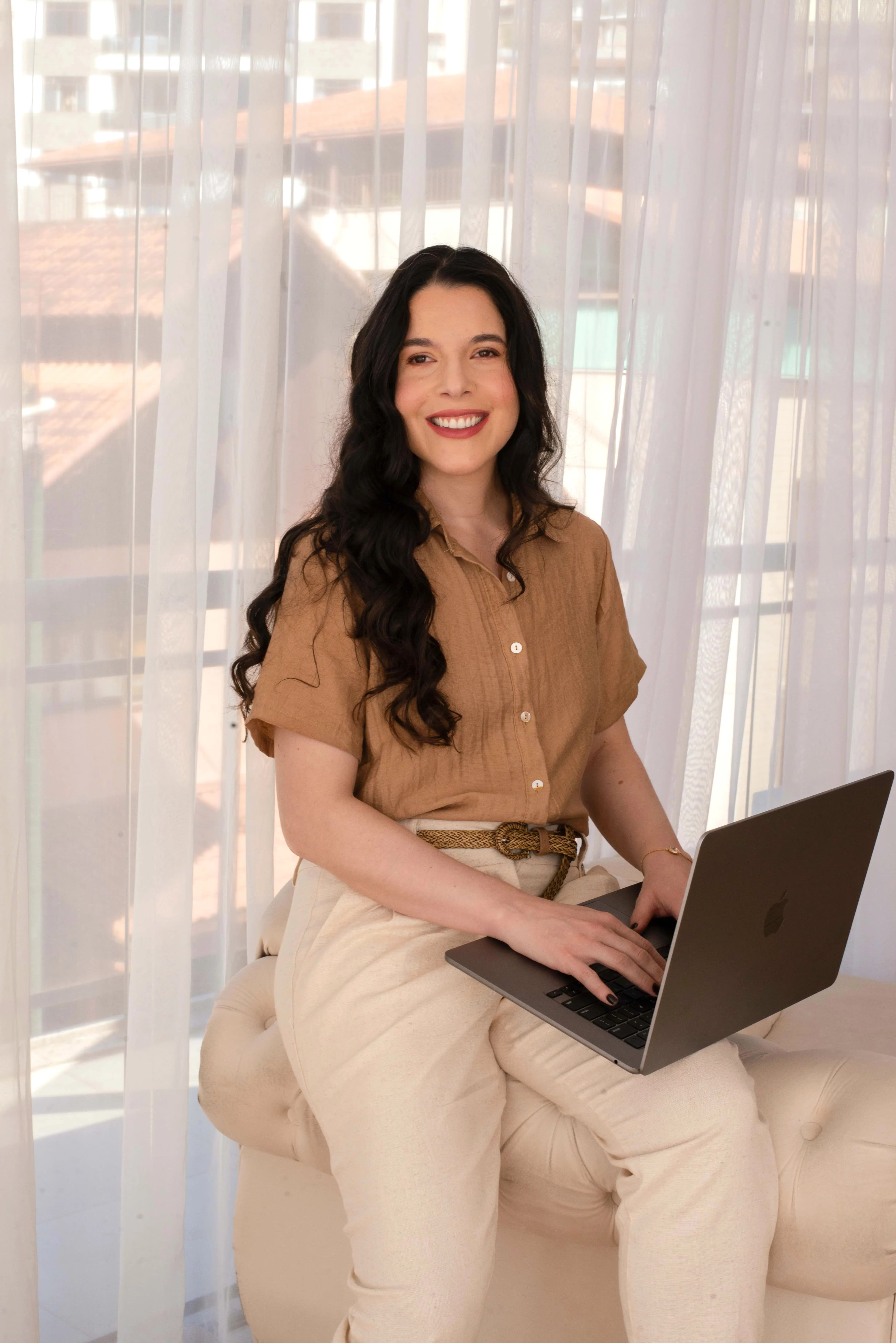 Retrato em estúdio com fundo bege, pessoa sorrindo de frente.